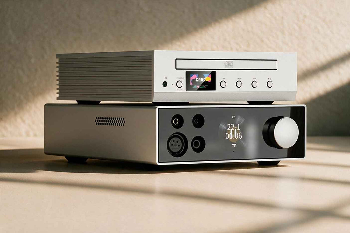 A portable digital audio player and small DAC components resting on a wooden table in warm raking light with long shadows.