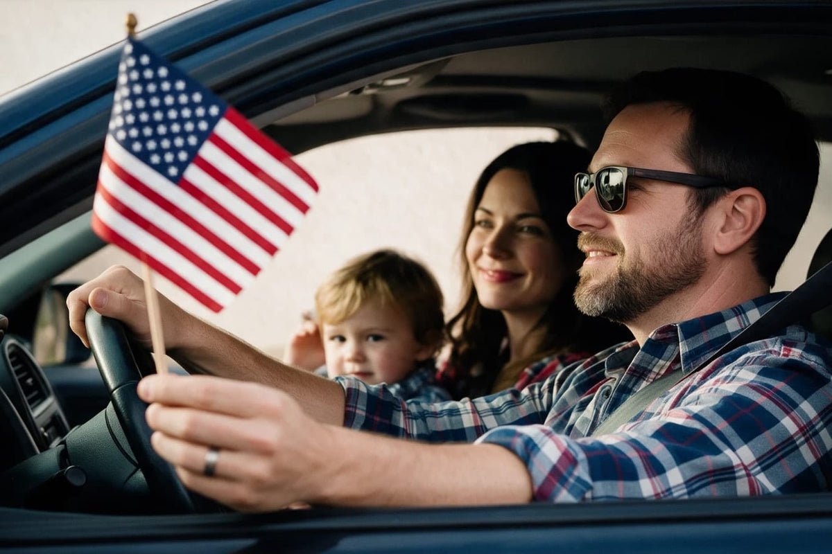 A family in a car, the driver holding a small United States flag at the steering wheel