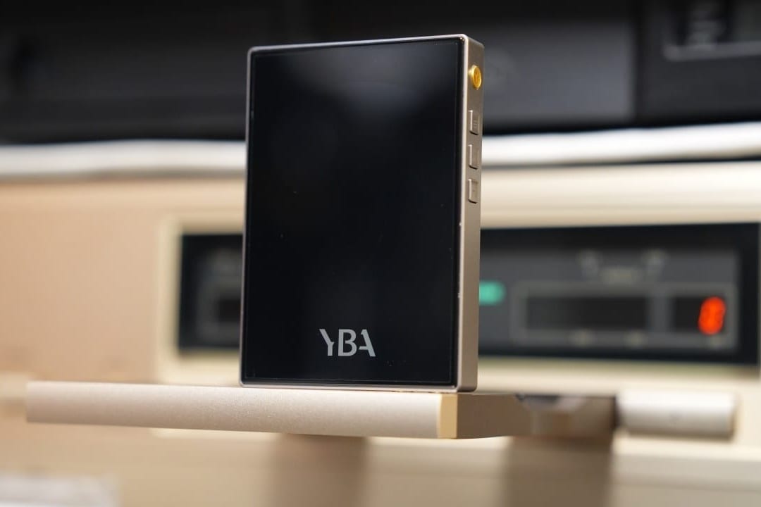 YBA VIBE P1 portable DAC/amp standing on the edge of a champagne-gold CD player