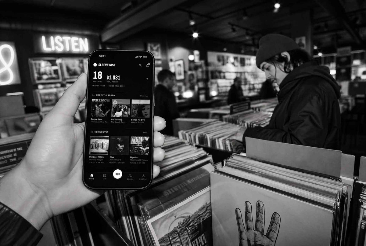 a man holds his phone with app sleevewise in a record shop