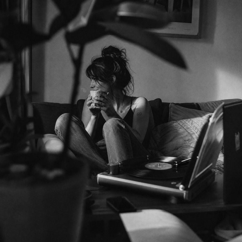 A woman on her couch with a coffee while a record plays.