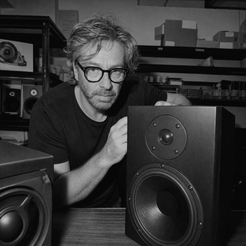 A speaker designer at his workbench with a bookshelf speaker.